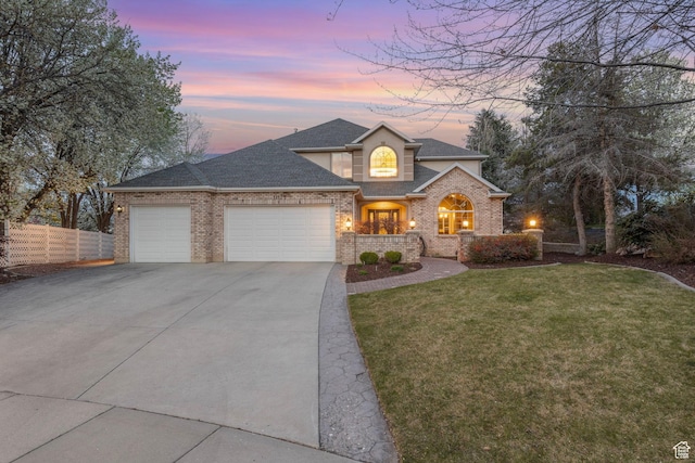 traditional-style home with roof with shingles, fence, concrete driveway, an attached garage, and a lawn