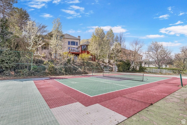 view of tennis court featuring community basketball court and fence