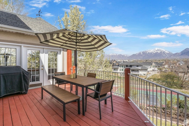 wooden terrace with a residential view, outdoor dining area, a grill, and a mountain view