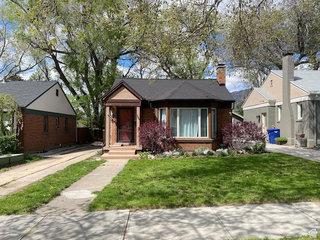 bungalow-style house featuring brick siding and a front yard