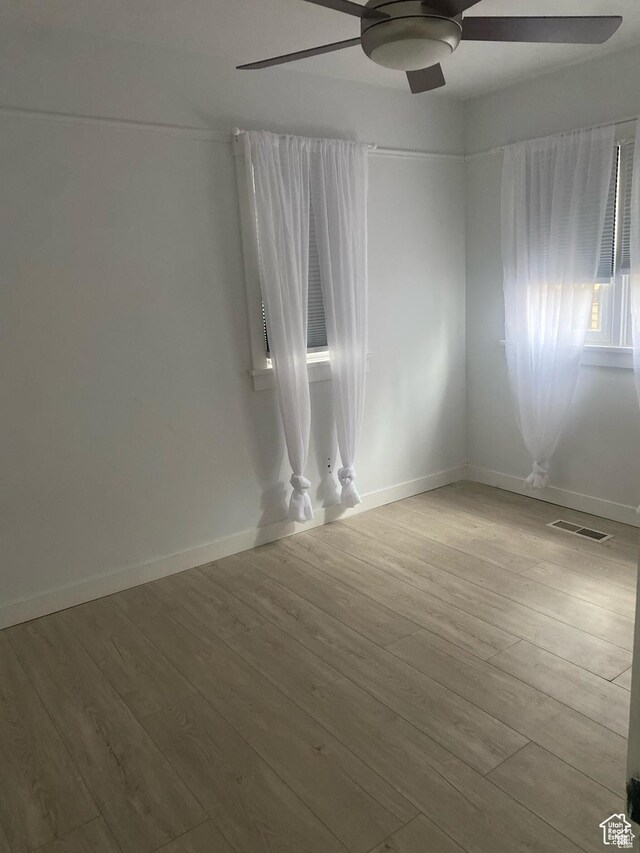 unfurnished room with baseboards, wood finished floors, visible vents, and ceiling fan