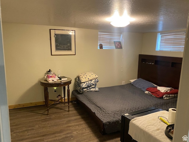 bedroom featuring wood finished floors, a textured ceiling, and baseboards