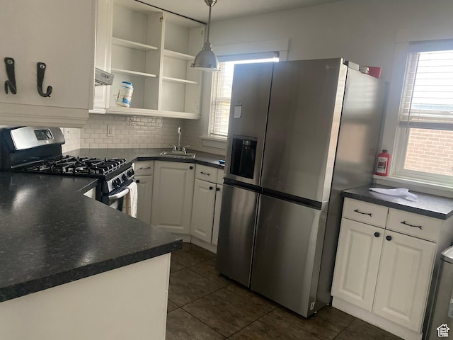 kitchen with dark countertops, a sink, decorative backsplash, appliances with stainless steel finishes, and white cabinetry