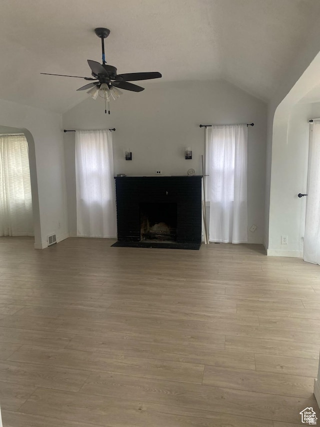 unfurnished living room with lofted ceiling, a ceiling fan, visible vents, and light wood-style flooring