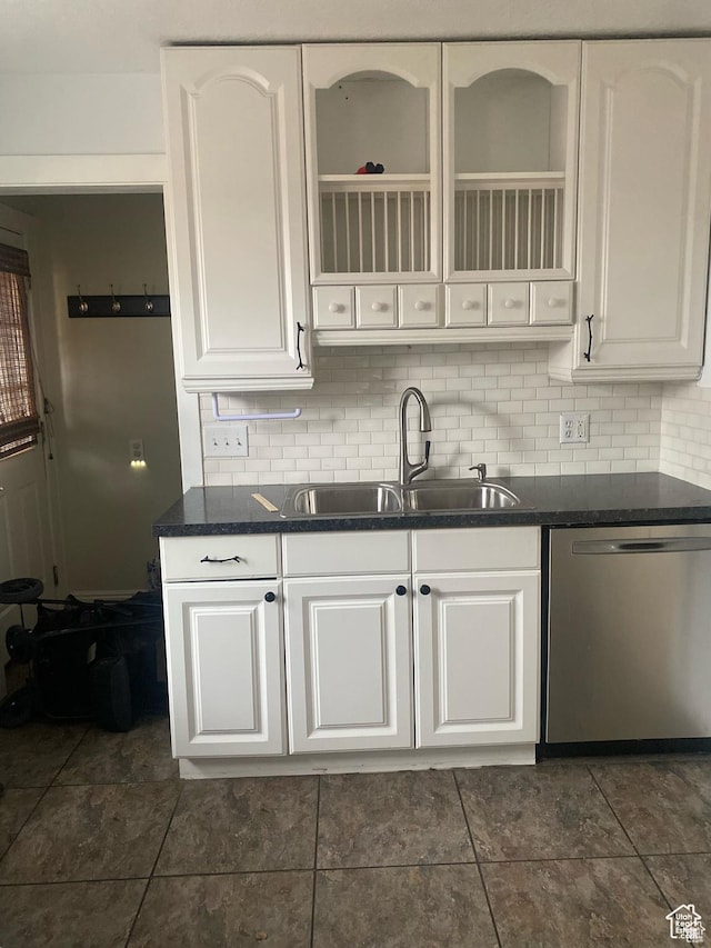 kitchen featuring dark countertops, dishwasher, tasteful backsplash, and a sink
