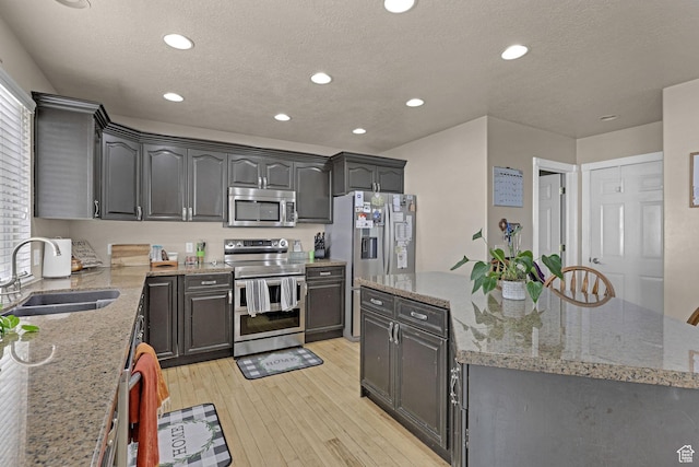 2838 N 1375 E, North Ogden, UT 84414 - kitchen with a center island, a sink, a textured ceiling, light wood finished floors, and appliances with stainless steel finishes