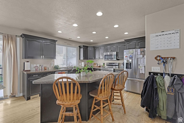 2838 N 1375 E, North Ogden, UT 84414 - kitchen with a center island, a textured ceiling, appliances with stainless steel finishes, and a kitchen breakfast bar
