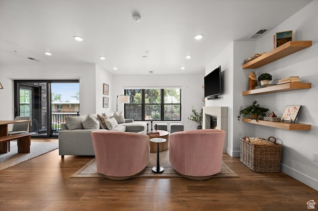 living room with recessed lighting, a glass covered fireplace, visible vents, and hardwood / wood-style flooring