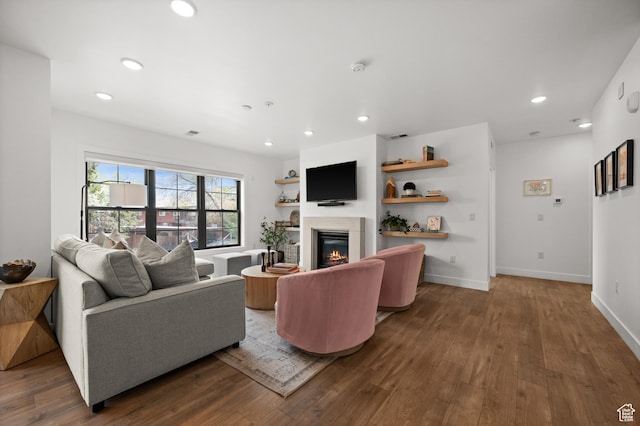 living area featuring a glass covered fireplace, wood finished floors, and recessed lighting