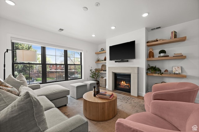 living room with recessed lighting, a glass covered fireplace, wood finished floors, and visible vents