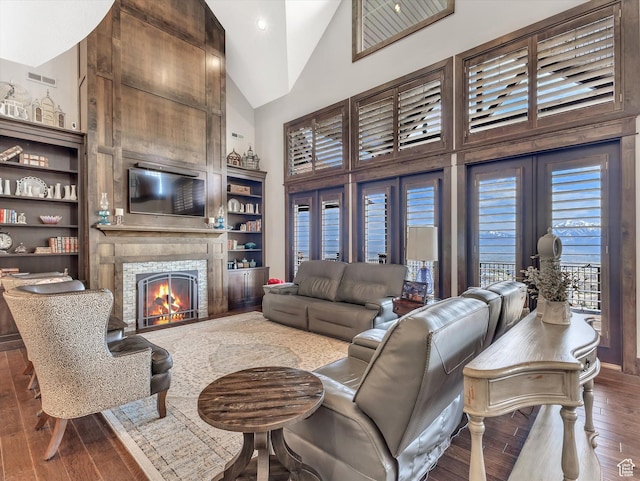 15146 S Secret Canyon Cir, Herriman, UT 84096 - living area with a tile fireplace, hardwood / wood-style floors, visible vents, built in features, and high vaulted ceiling