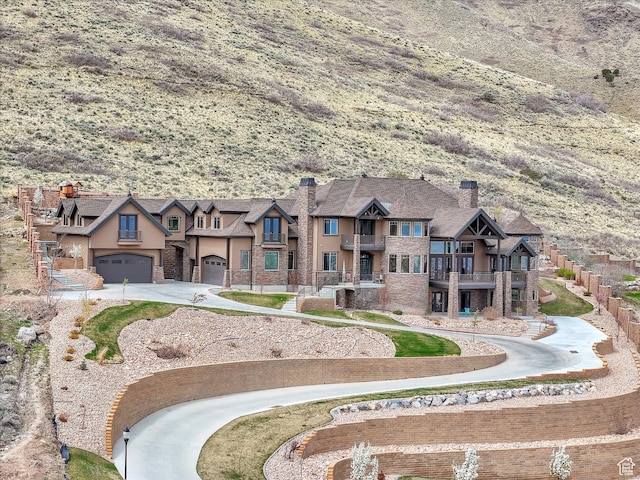 15146 S Secret Canyon Cir, Herriman, UT 84096 - view of front of home featuring a balcony, a chimney, driveway, stone siding, and stucco siding