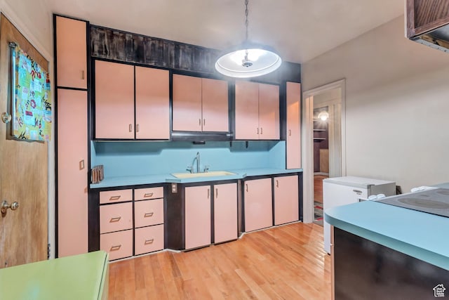 2481 Van Buren Ave, Ogden, UT 84401 - kitchen featuring light wood finished floors, light countertops, a sink, and hanging light fixtures