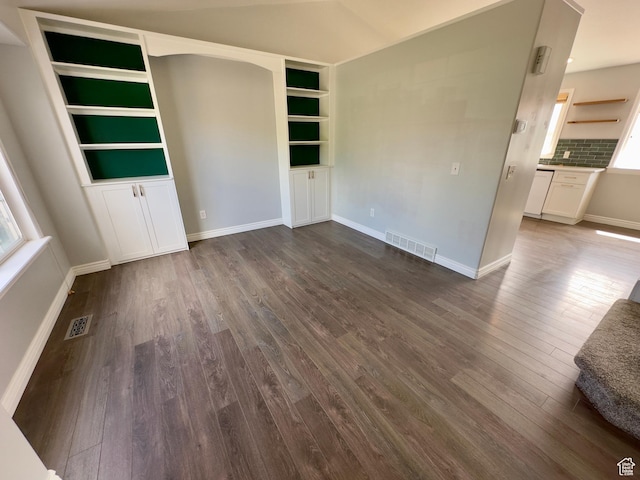 unfurnished living room with dark wood-style flooring, baseboards, and built in features