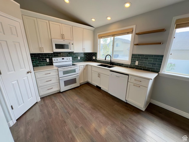 kitchen with white appliances, a sink, white cabinets, backsplash, and light countertops