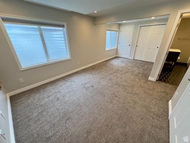 unfurnished bedroom featuring carpet, multiple closets, baseboards, and recessed lighting