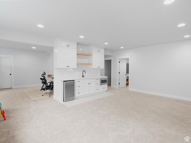 kitchen featuring stainless steel microwave, beverage cooler, open shelves, white cabinetry, and open floor plan
