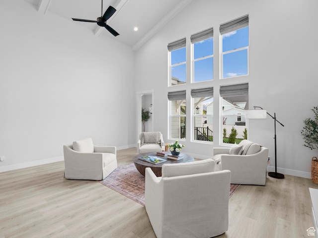 living area with high vaulted ceiling, light wood-type flooring, baseboards, a ceiling fan, and beamed ceiling