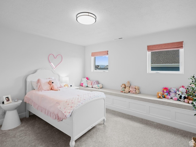 bedroom with light colored carpet and a textured ceiling