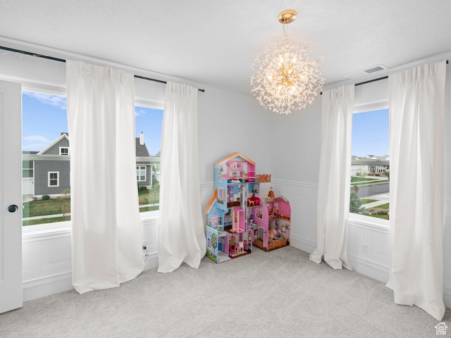 game room featuring carpet floors, a chandelier, wainscoting, and a decorative wall