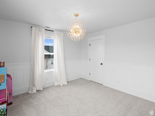 unfurnished room with a chandelier, carpet, a wainscoted wall, and a decorative wall