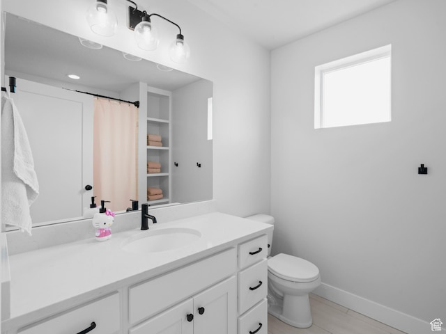 bathroom featuring vanity, toilet, baseboards, and tile patterned flooring