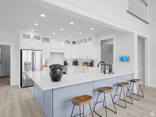 kitchen featuring high quality appliances, light wood-type flooring, tasteful backsplash, a breakfast bar, and recessed lighting