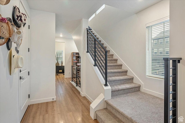 foyer with stairway, baseboards, light wood finished floors, and recessed lighting
