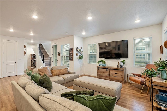living area featuring light wood finished floors, baseboards, recessed lighting, and stairway