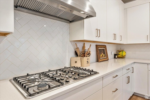 kitchen featuring premium range hood, light countertops, backsplash, and stainless steel gas cooktop