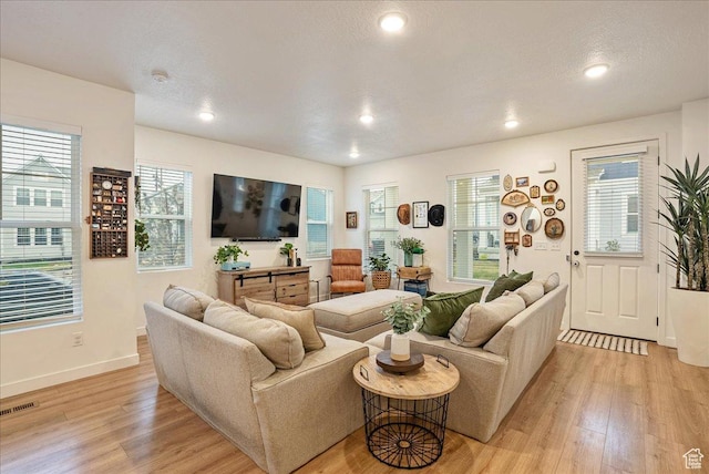 living room with a healthy amount of sunlight, light wood-style floors, visible vents, and recessed lighting