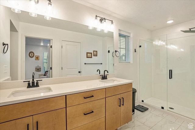 bathroom featuring double vanity, marble finish floor, a stall shower, and a sink