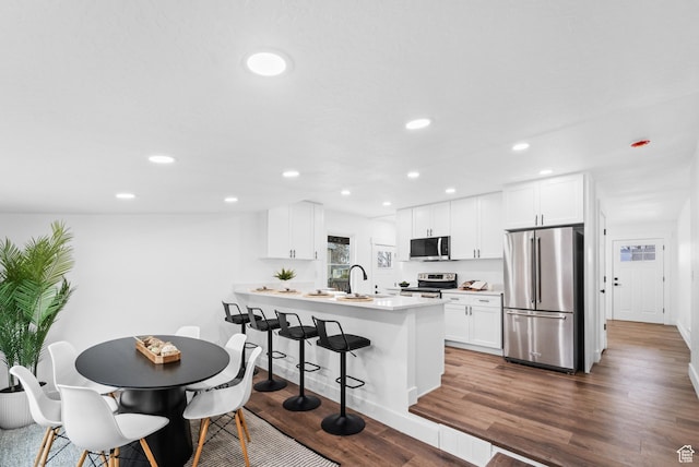 1131 W Simondi Ave N, Salt Lake City, UT 84116 - kitchen with a peninsula, dark wood-style flooring, recessed lighting, a kitchen bar, and appliances with stainless steel finishes