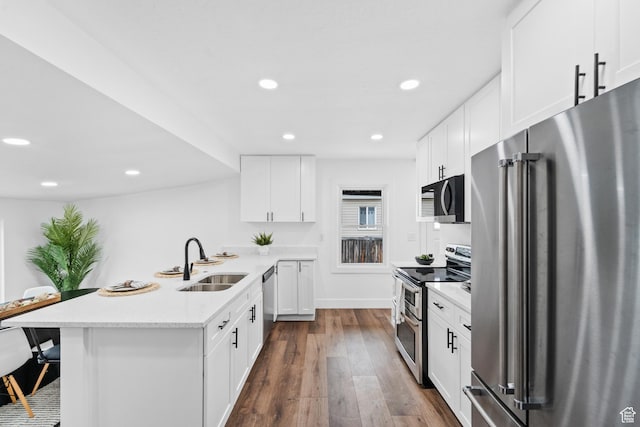 1131 W Simondi Ave N, Salt Lake City, UT 84116 - kitchen featuring a peninsula, a sink, dark wood finished floors, appliances with stainless steel finishes, and a breakfast bar area