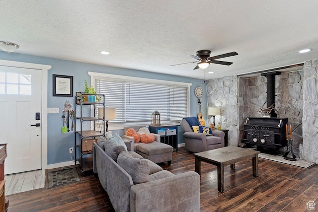 living area featuring a wood stove, wood-type flooring, and a textured ceiling