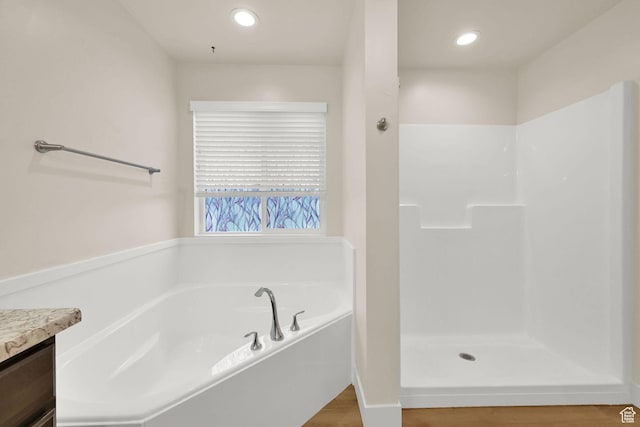 full bath with recessed lighting, walk in shower, a bath, vanity, and wood finished floors