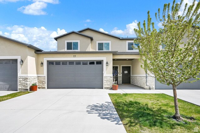 view of front of property featuring stone siding, an attached garage, driveway, and stucco siding