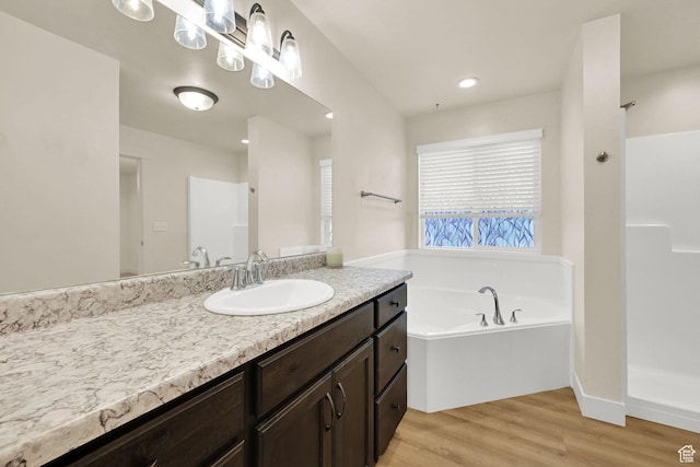 full bath with walk in shower, wood finished floors, vanity, recessed lighting, and a garden tub