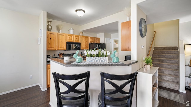 6661 W Merlot Way, West Jordan, UT 84081 - kitchen with black appliances, dark wood-style flooring, a kitchen breakfast bar, and dark countertops