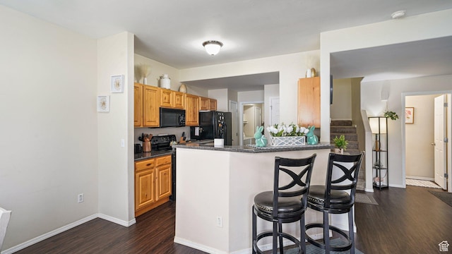 6661 W Merlot Way, West Jordan, UT 84081 - kitchen featuring dark wood-style floors, a breakfast bar, baseboards, black appliances, and a peninsula