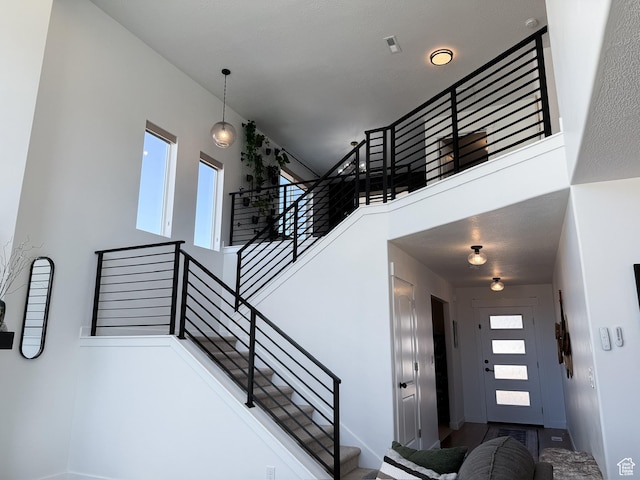 stairway featuring a high ceiling and baseboards