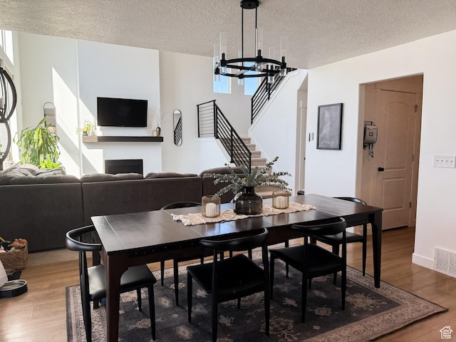 dining space with a notable chandelier, visible vents, a fireplace, and light wood-style floors