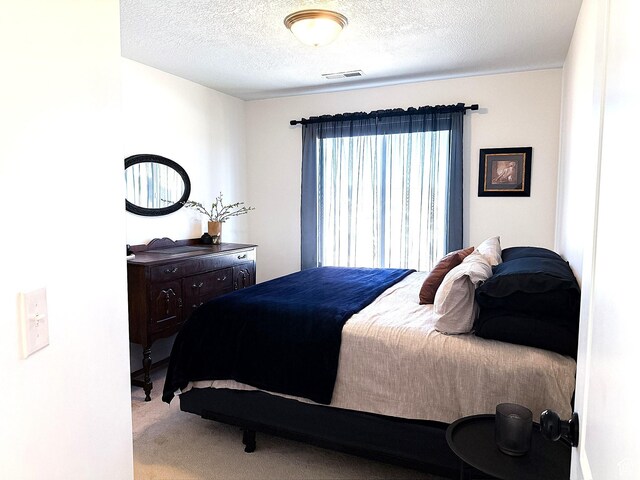 carpeted bedroom featuring visible vents and a textured ceiling