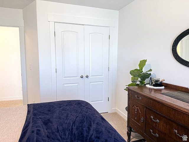 bedroom with baseboards, a closet, and light colored carpet