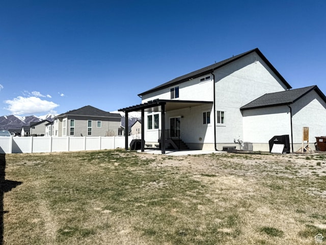 rear view of property featuring a lawn, a pergola, fence, and stucco siding