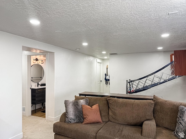 living room with recessed lighting, visible vents, baseboards, a textured ceiling, and light colored carpet