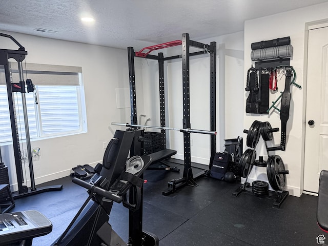 workout area with baseboards, visible vents, and a textured ceiling