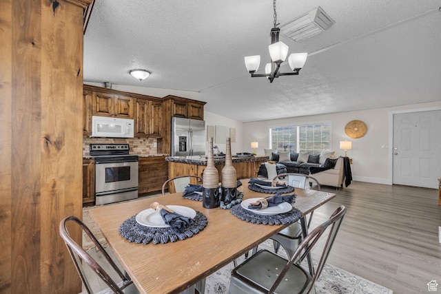 345 E 100 S, Coalville, UT 84017 - dining space with a textured ceiling, light wood-style flooring, baseboards, an inviting chandelier, and vaulted ceiling