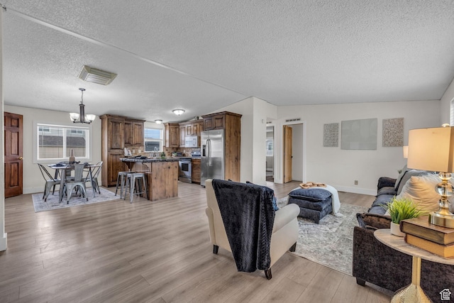 345 E 100 S, Coalville, UT 84017 - living area with a textured ceiling, visible vents, light wood-style floors, baseboards, and a notable chandelier