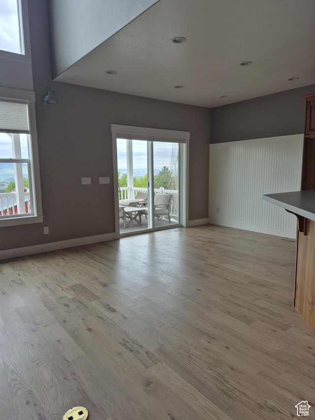 unfurnished living room with plenty of natural light, light wood-type flooring, recessed lighting, and baseboards